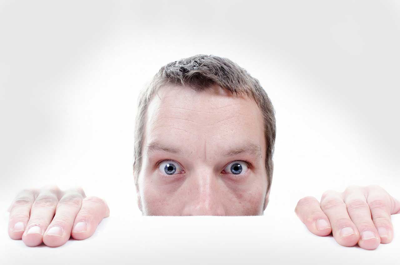 Man peering up from behind desk