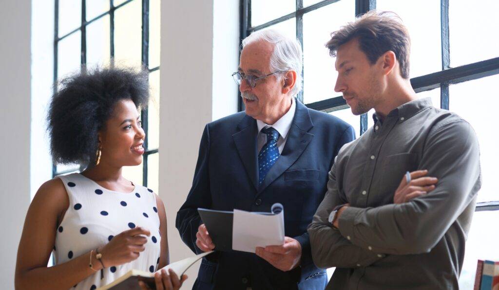 Senior employee talking to two younger colleagues