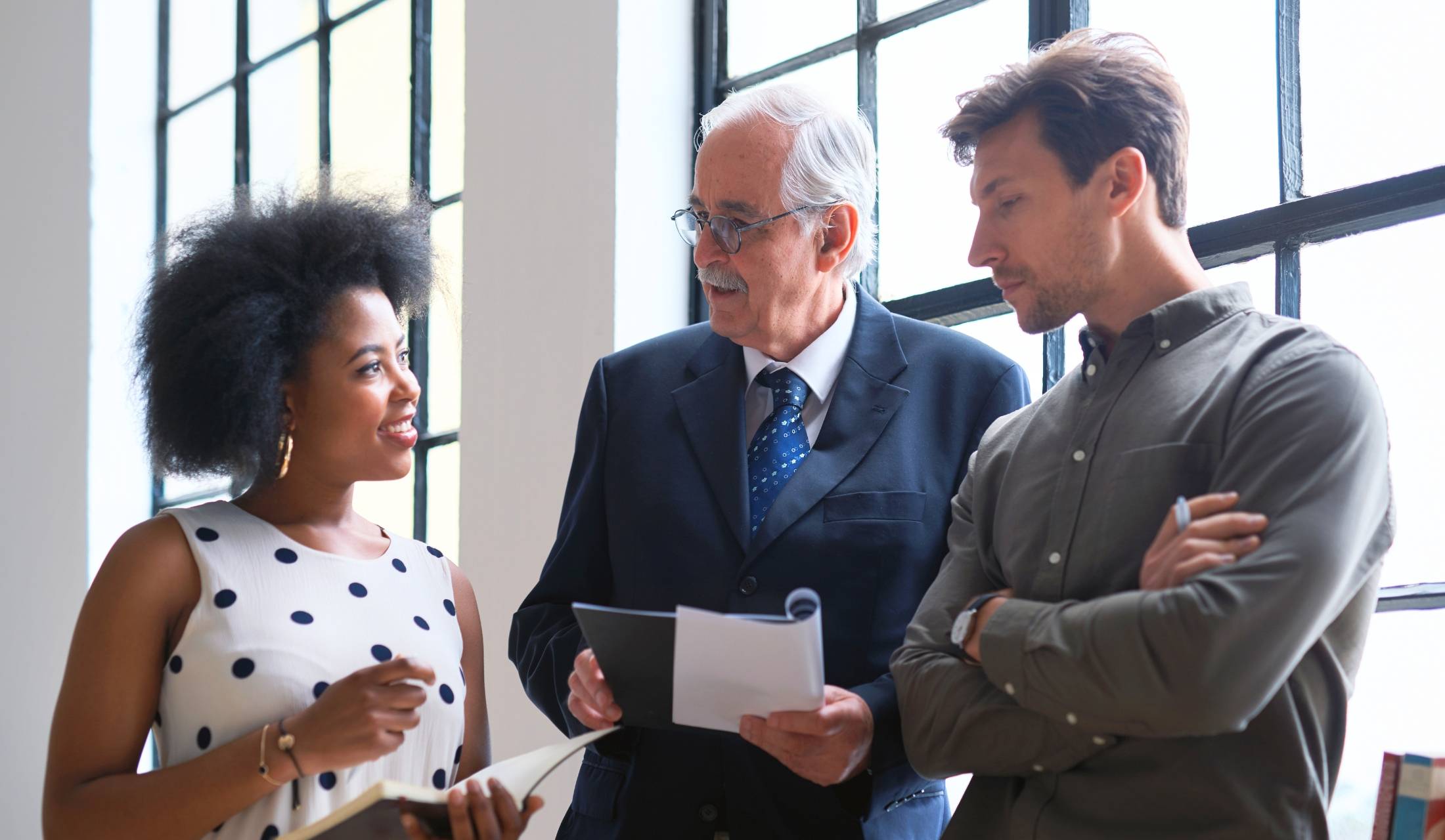 Senior employee talking to two younger colleagues