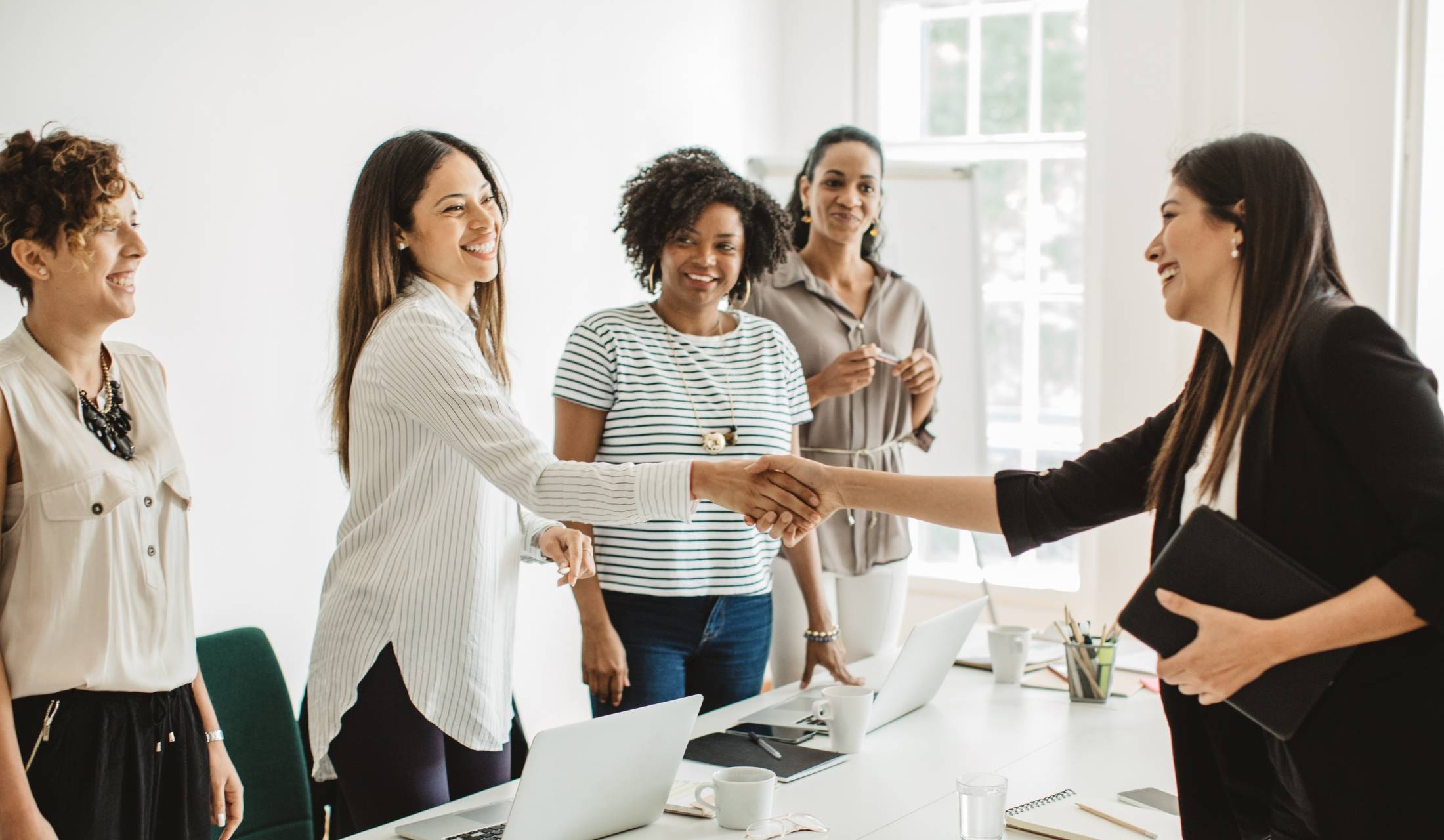 Woman starting a new job shaking hands with coworkers